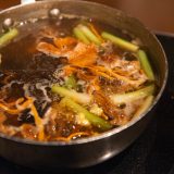 A bowl of mushrooms and vegetables in a broth.