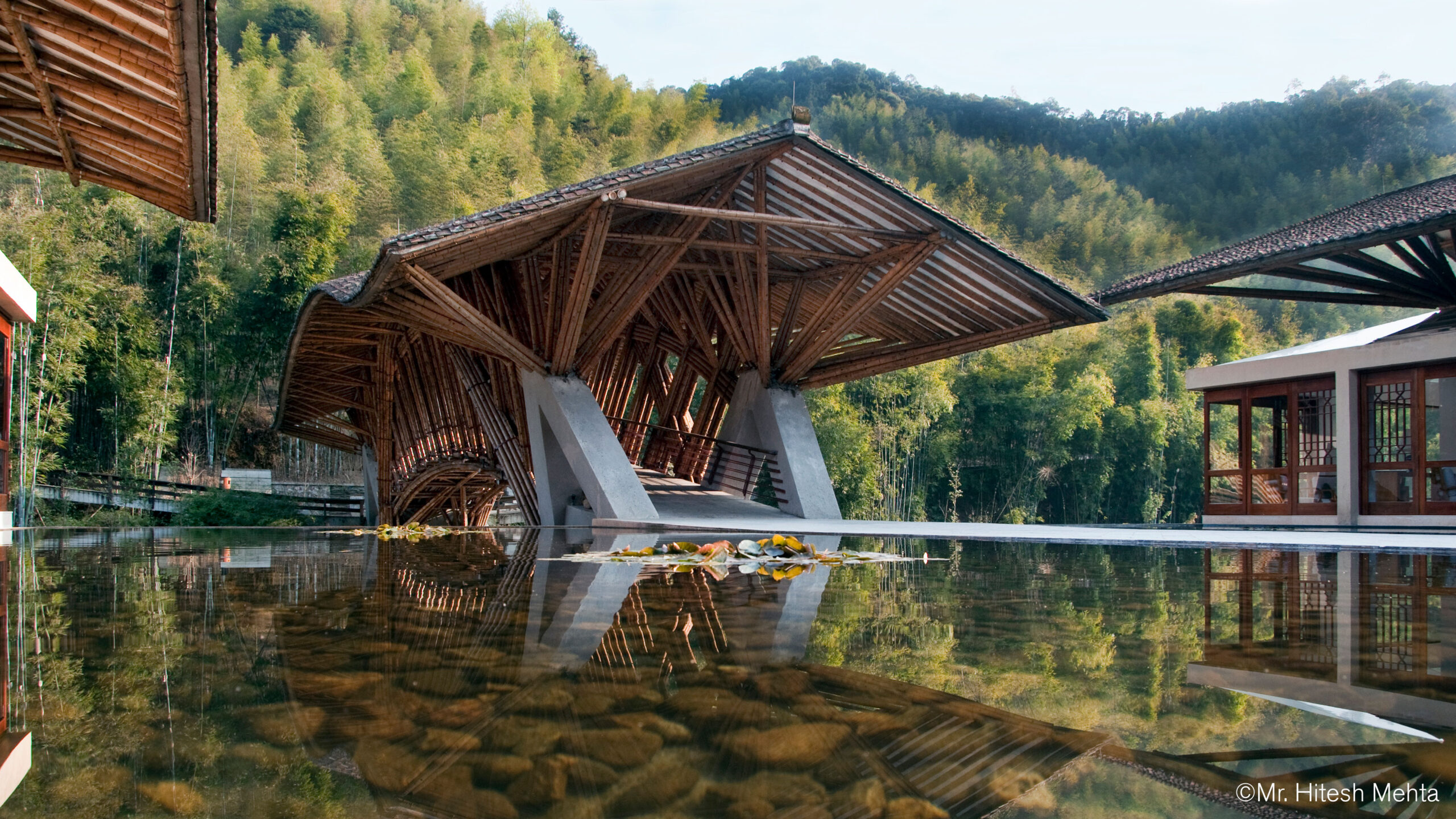 A unique series of roofed outdoor structures butts up against a shallow water feature in nature