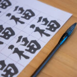 a piece of paper with Chinese characters next to a brush used to draw these characters