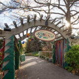 A wooden gate with colorful ribbons leads into a children's garden