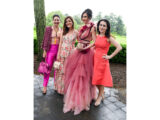 Four people in bright pink cocktail dresses pose for a photo