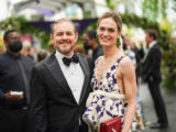 Two people in evening attire pose for a photo outdoors