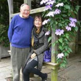 two people sitting on a bench surrounded by purple flowers