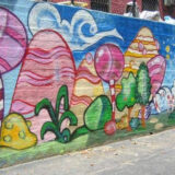 an image of a colorful mural featuring small green trees and large yellow and pink rocks