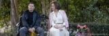 A still of Sigourney Weaver in a white skirt and floral cardigan sitting on a bench alongside Joel Edgerton, dressed in all black.