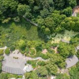 Aerial view of green tree tops, green marsh areas, and top of buildings and pathways of a space that is identified as the Everett Children's Adventure Garden.