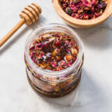 A jar of honey filled with dried botanicals