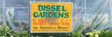 a yellow sign for Bissel Garden, a local Bronx community garden, attached to a green house with green plants below the sign