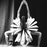 a person in a dance pose featuring white decorative tubes in the costume that resemble a flower