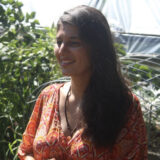 A person in an orange sundress poses for a photo outdoors