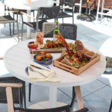 a white table and three chairs, displaying Pecao Frito, a Caribbean dish, by the restaurant Jalao