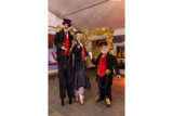 Three people dressed as stilt-walking train conductors pose for a photo