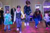 Five children dance energetically on a wooden dance floor