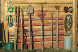 A shed with different gardening tools leaned against it