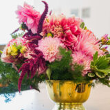 An arrangement of pink flowers in a golden bowl