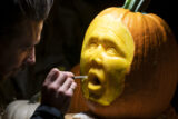 a person carves a jack-o-lantern with a human face in the dark