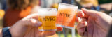 two hands cheerings tiny beer glasses with the NYBG logo on them