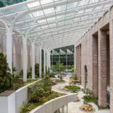 An overhead view of a planted outdoor corridor featuring arching glass over top