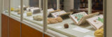 A glass enclosure displaying antique books and skeins of different yarns