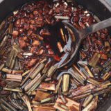 A bowl of brown spices and herbs with a spoon