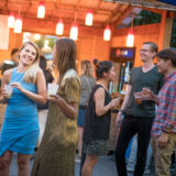 people mingling near a bar with drinks in hand