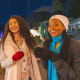 two people in winter coats standing next to each other holding beverages