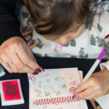 a child colors in a card that has botanical stamps on it