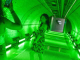 Two people pose for photos in a long, green-lit tunnel