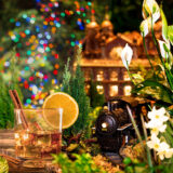 A cocktail in a tumbler sits alongside a model train track in a holiday setting