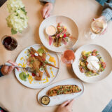 A top-down shot of a table set with plates of food and wine