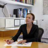 A person in a dark sweater is photographed while working at an office desk