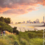 A waterside view of a city skyline at sunset