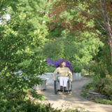 A person using a wheelchair explores a verdant garden space