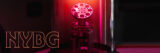 A piece of scientific machinery inside a glass tube, lit with red, with the letters 'NYBG' overlaid in pink neon