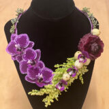 a necklace made out of purple orchids and other purple and green plants