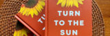 an orange book with the an image of yellow petals of a sunflower with the title "Turn to the Sun" in white font