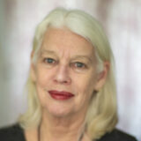A person with long white hair poses for a headshot