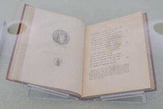 A poem in an old book displayed in a case.