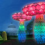Two large, glowing multicolored mushrooms on the lawn in front of the Conservatory.
