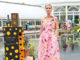 a person in a pink floral dress poses in front of the Conservatory pool next to a Veuve Clicquot stand