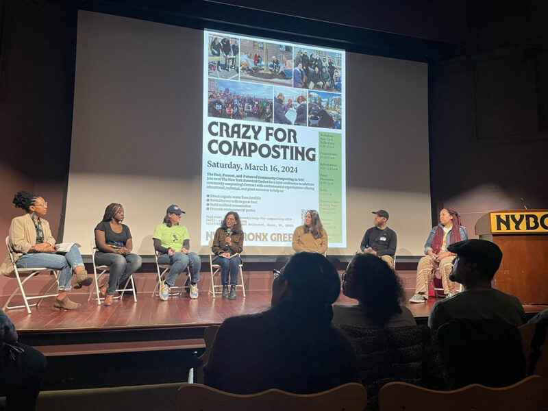 People sit on a lit stage for a panel discussion on composting