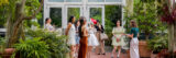 People gather for a tour in a lush green conservatory