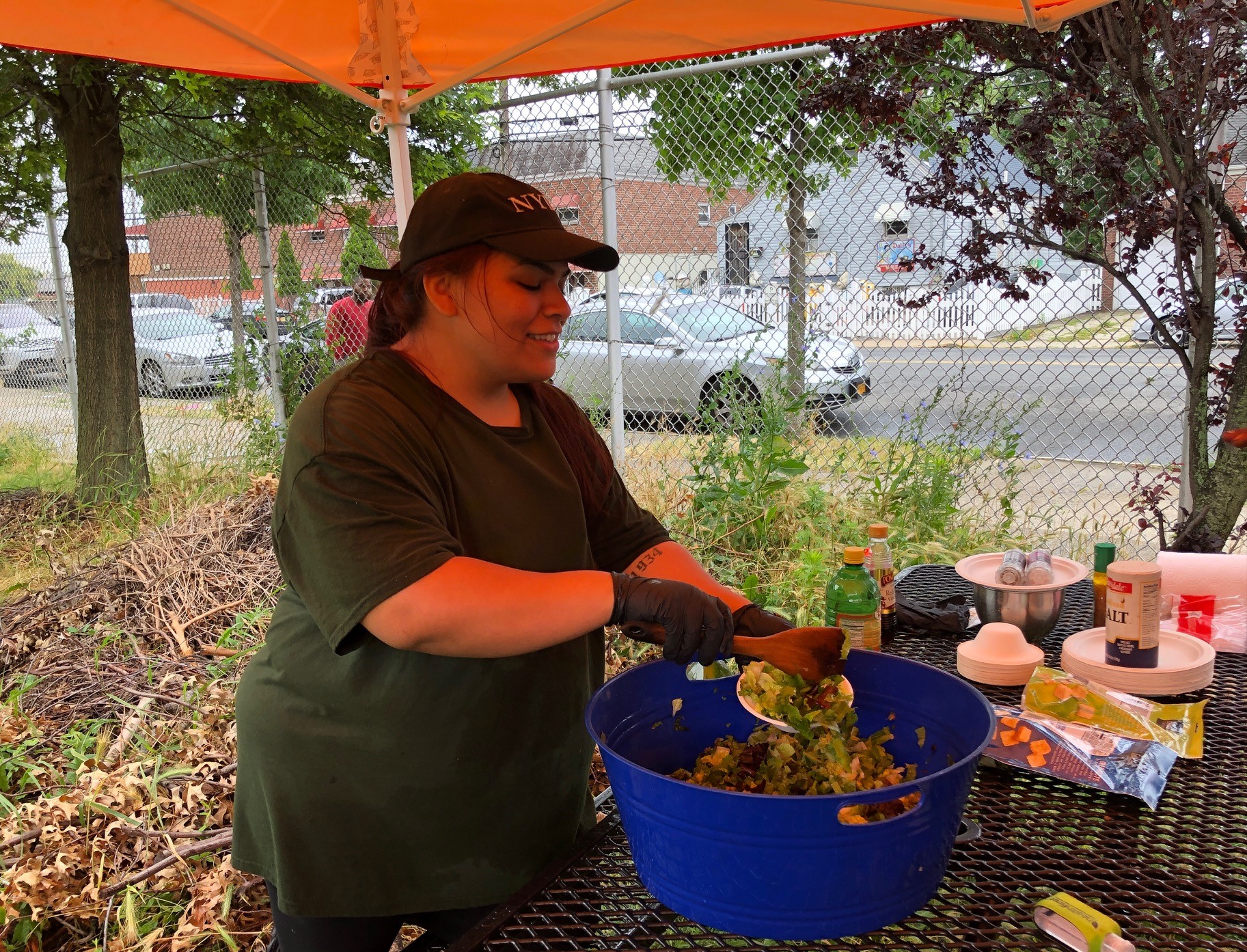 A person in a baseball cap works with compost during an outdoor event