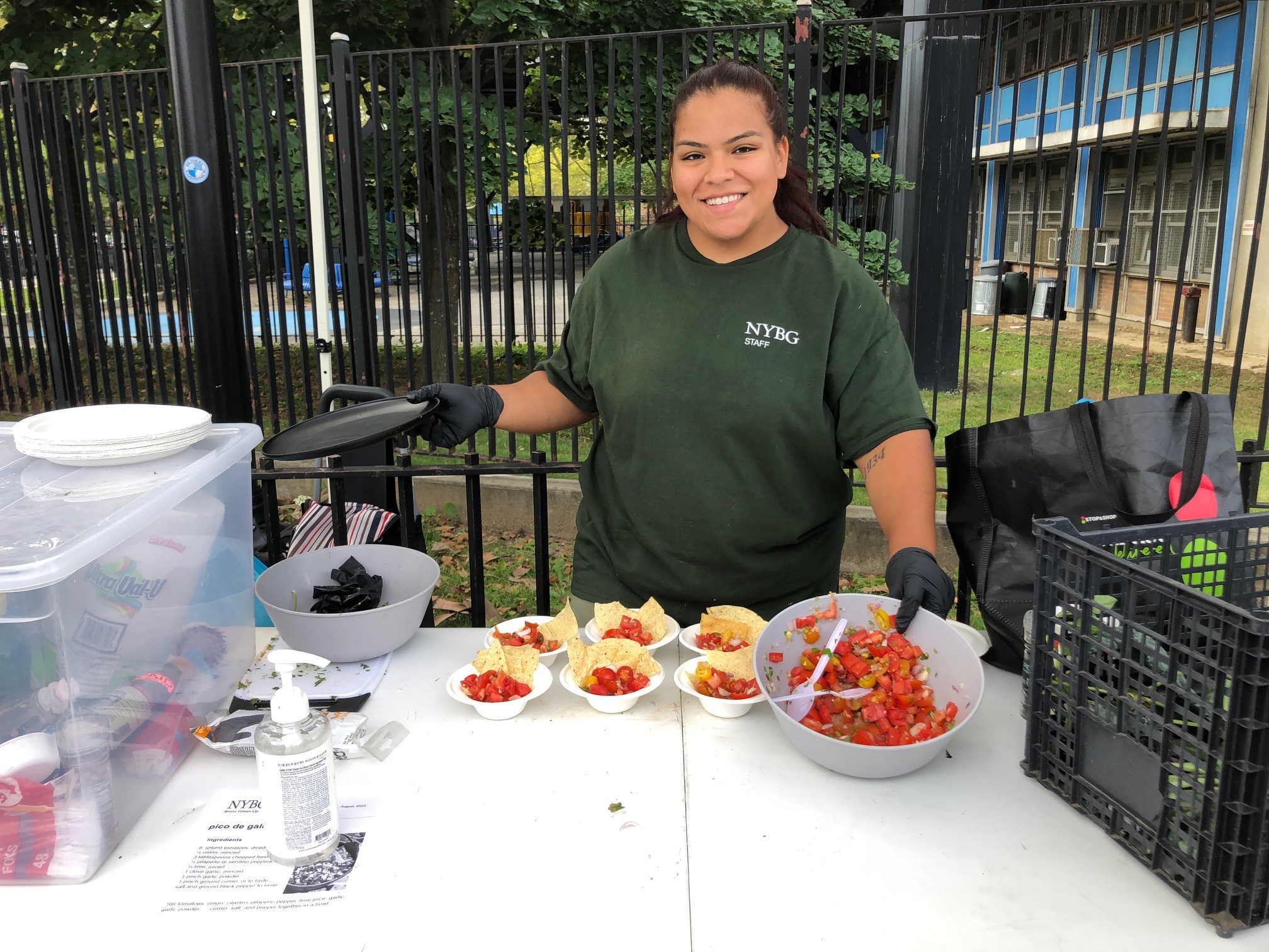 A person in a green shirt poses for a photo while showing the food they're preparing