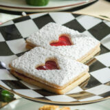 two cookies are on a black and white checkered plate with a heart imprinted on the top