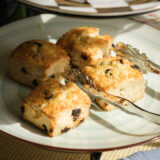 four raisin scones are placed on a white plate