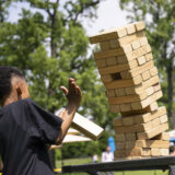 A child in a black shirt reacts as a large tower of jenga blocks comes crashing down during a game
