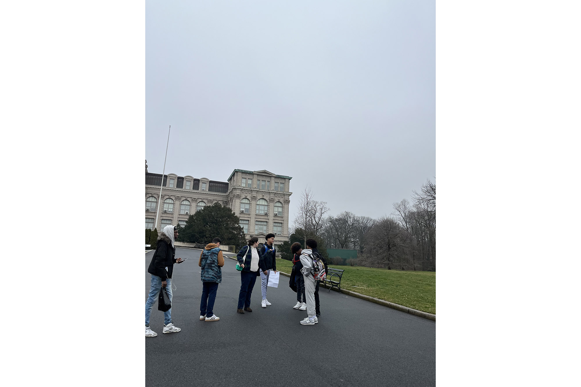 Students walk along a path in front of a classically designed building