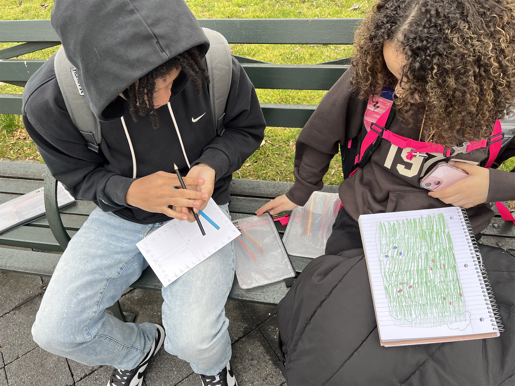 Students sit on a bench outdoors, working together on a map