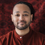 A person in a red shirt poses for a headshot